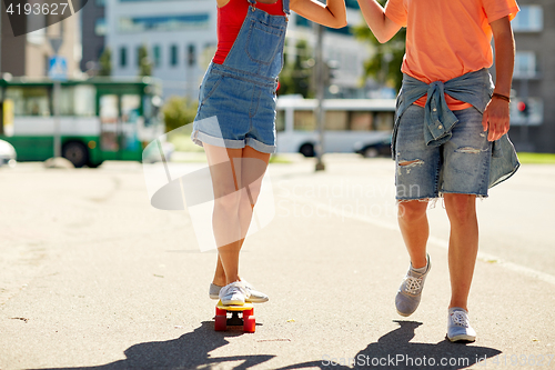 Image of teenage couple riding skateboard on city street