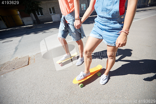 Image of teenage couple riding skateboards on city street