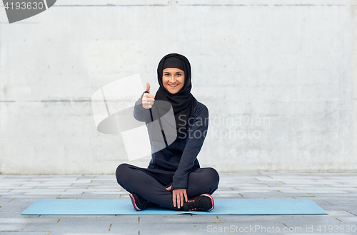 Image of muslim woman doing sport and showing thumbs up