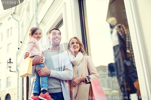 Image of happy family with child and shopping bags in city