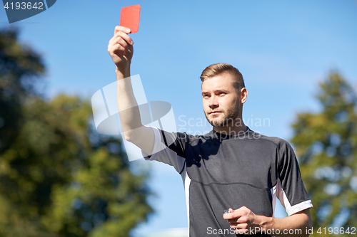 Image of referee on football field showing yellow card