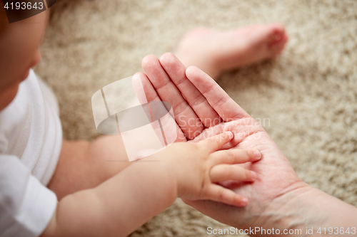 Image of close up of little baby and mother hands