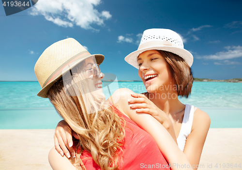 Image of happy young women in hats on summer beach