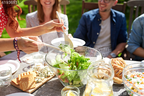 Image of happy friends having dinner at summer garden party