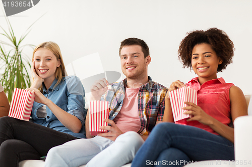 Image of happy friends with popcorn watching tv at home