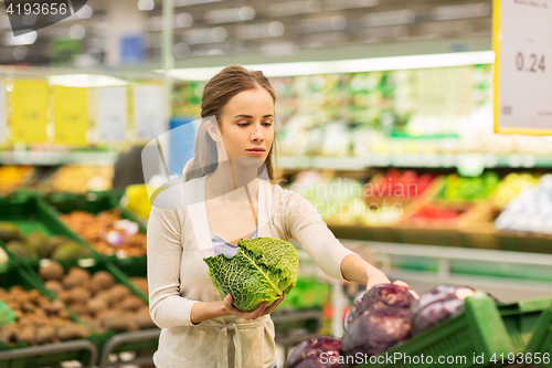 Image of happy woman buying savoy at grocery store