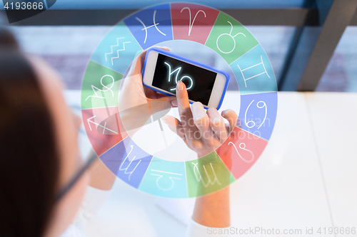 Image of woman with smartphone and zodiac signs at office