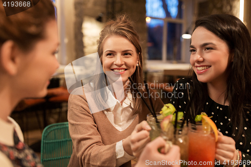 Image of happy friends clinking drinks at restaurant