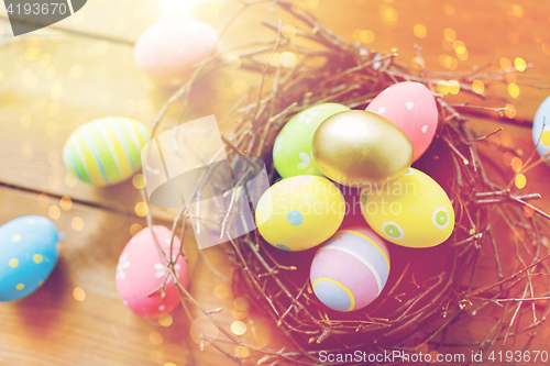 Image of close up of colored easter eggs in nest on wood