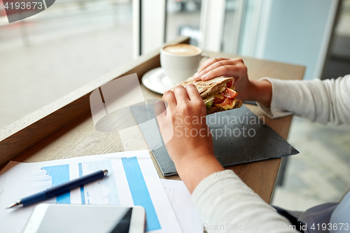 Image of woman eating salmon panini sandwich at cafe