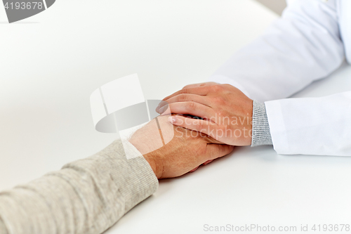 Image of close up of doctor holding old man hand