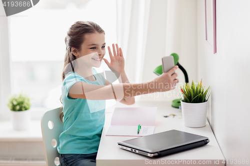 Image of happy girl with smartphone taking selfie at home