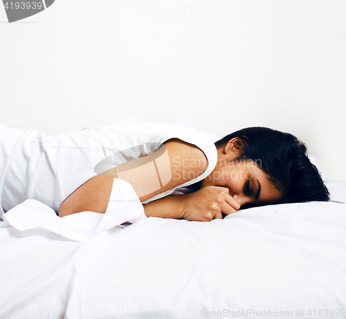 Image of young pretty tann woman in bed among white sheets having fun, trying to sleep, fooling around, lifestyle concept at home