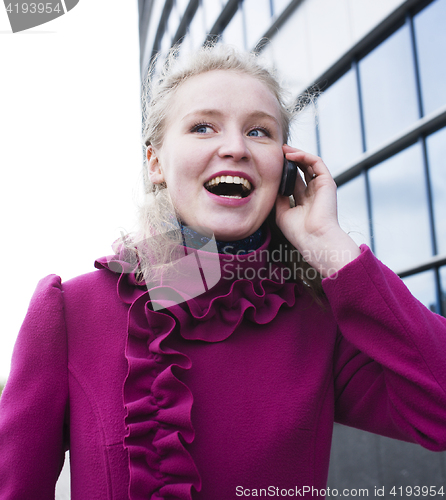 Image of pretty blond woman talking emotional on phone outside near modern building, lifestyle people concept