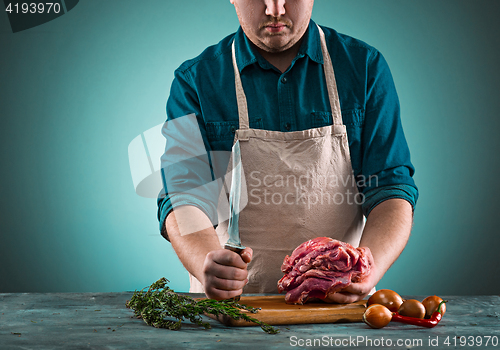 Image of Butcher cutting pork meat on kitchen