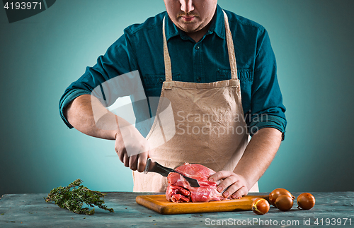 Image of Butcher cutting pork meat on kitchen