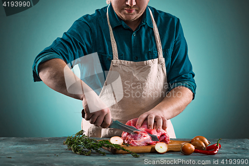 Image of Butcher cutting pork meat on kitchen