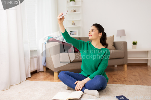 Image of woman with smartphone taking selfie at home