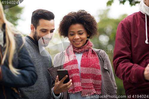 Image of happy friends with smartphone outdoors