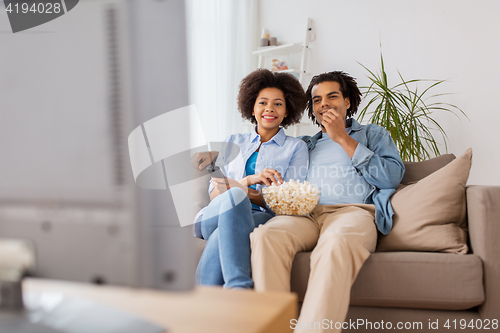 Image of smiling couple with popcorn watching tv at home