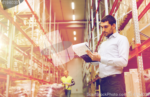 Image of businessman writing to clipboard at warehouse