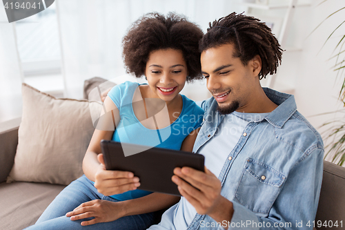 Image of smiling happy couple with tablet pc at home