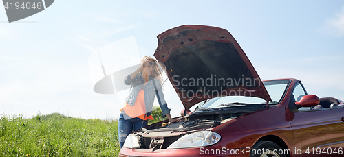 Image of woman with open hood of broken car at countryside