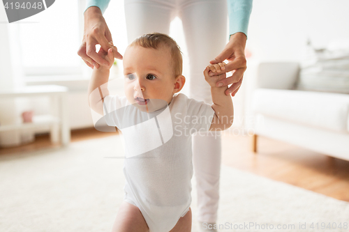 Image of happy baby learning to walk with mother help