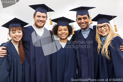 Image of happy students or bachelors in mortar boards