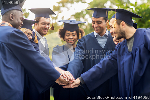 Image of happy students in mortar boards with hands on top