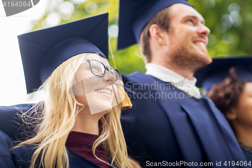 Image of happy students or bachelors in mortar boards