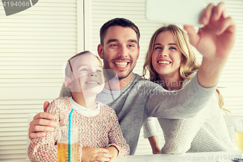 Image of happy family taking selfie at restaurant