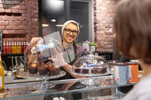 Image of man or barman with cakes serving customer at cafe