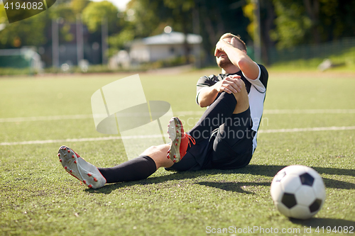 Image of injured soccer player with ball on football field