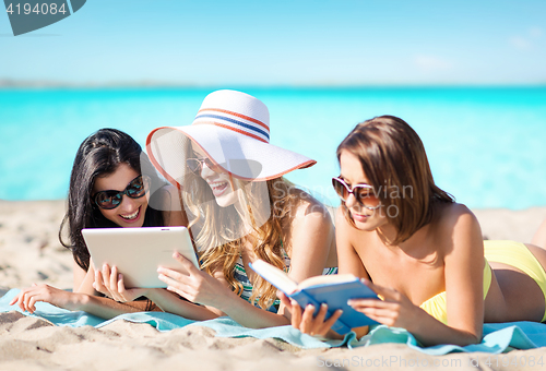 Image of women with tablet pc and book on summer beach