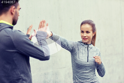 Image of happy woman with coach working out strike outdoors