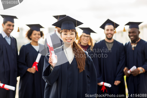 Image of happy students in mortar boards with diplomas