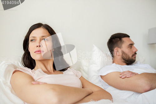 Image of unhappy couple having conflict in bed at home