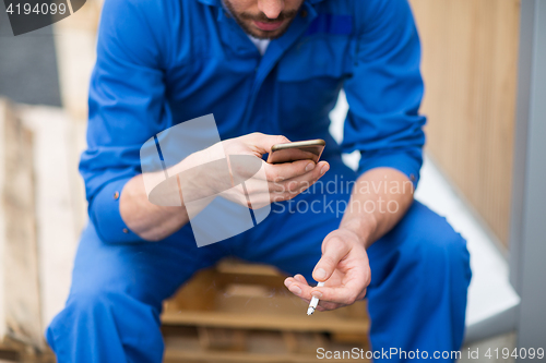 Image of auto mechanic smoking cigarette at car workshop