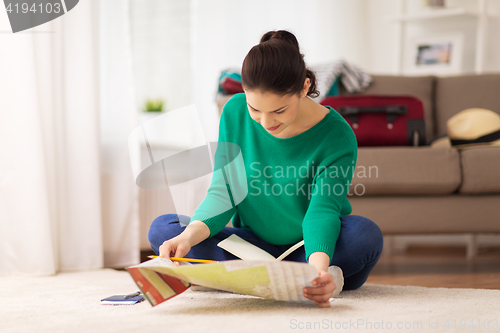 Image of woman with notebook and travel map at home