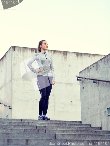 Image of smiling sportive woman on stairs at city