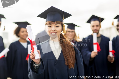 Image of happy students in mortar boards with diplomas