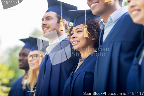 Image of happy students or bachelors in mortar boards