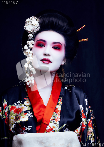 Image of young pretty real geisha in kimono with sakura and decoration