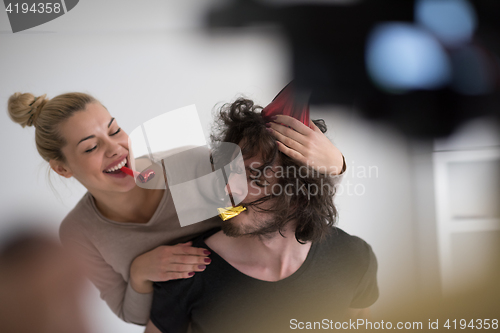 Image of couple in party hats blowing in whistle