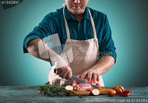 Image of Butcher cutting pork meat on kitchen