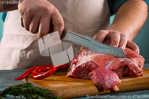 Image of Butcher cutting pork meat on kitchen