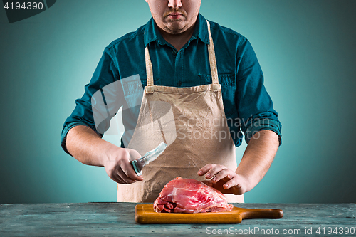 Image of Butcher cutting pork meat on kitchen