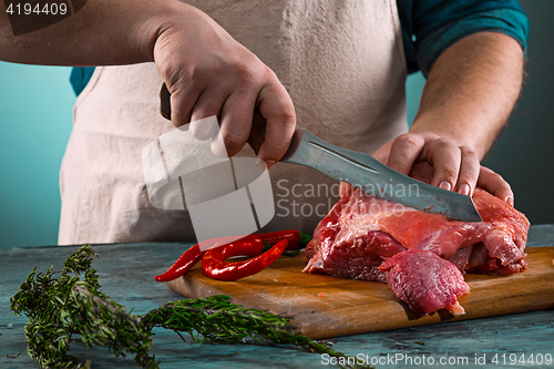 Image of Butcher cutting pork meat on kitchen