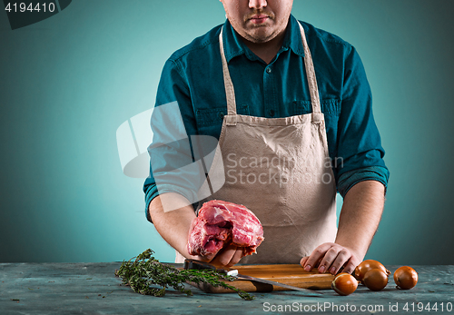 Image of Butcher cutting pork meat on kitchen